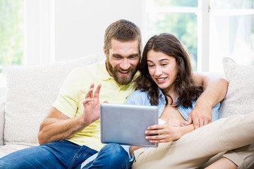 Couple sitting on sofa and using digital tablet in living room