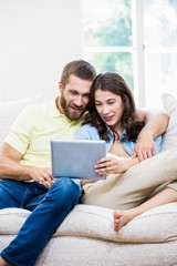 Couple using digital tablet in living room