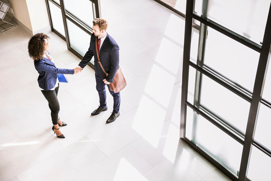 High angle view of businessman and woman shaking hands at  office entrance
