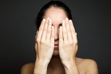 Young woman covering half of her face with a hand.