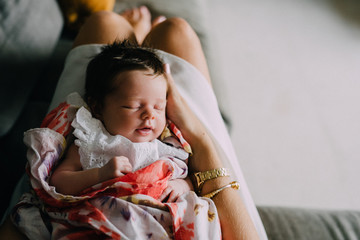 Mother resting new baby on legs, elevated view