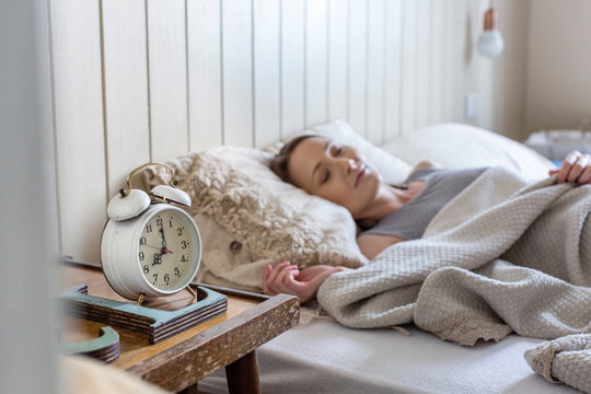 Woman in bed, alarm clock on bedside table
