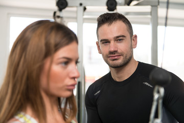 Fototapeta na wymiar Personal Trainer Helping Client In Gym