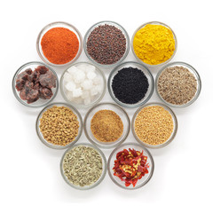 Different types of Indian spices in glass bowls isolated on white background. Top view.