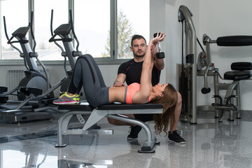 Fototapeta na wymiar Personal Trainer Helping Woman On Chest Exercise