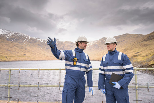 Workers on dam with water at hydroelectric power station