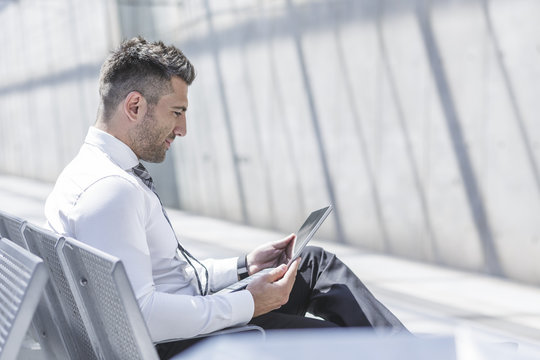 Businessman using digital tablet at waiting area