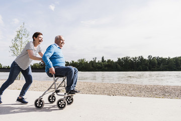 Woman pushing her old father sitting on wheeled walker