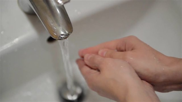 Woman washes her hands with soap in the bathroom, close-up