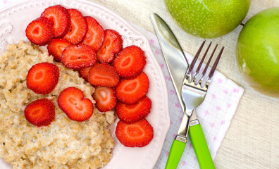 Oatmeal with strawberries and apples on the table. The view from