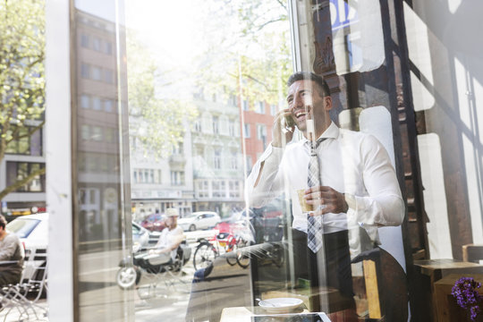 Happy businessman on cell phone in a cafe