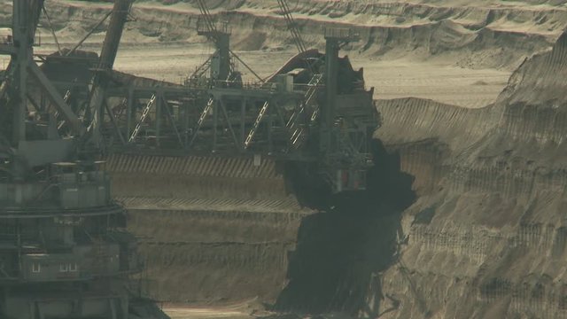 Open-cast mining. Giant bucket-wheel excavator. Wheel moves to the left. Medium shot. Surface mine. 