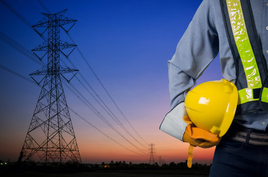 Engineer holding yellow helmet with Transmission tower.