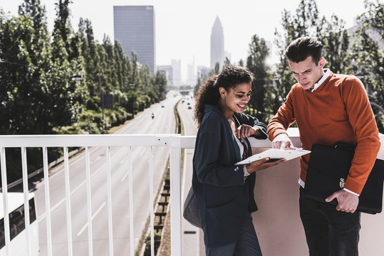 Young man and woman on bridge looking at document