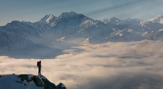 Climber on a peak emerging from fog in the Alps, Bettmeralp, Valais, Switzerland