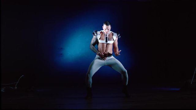 Muscular sexy naked man dancing in the studio on blue light background
