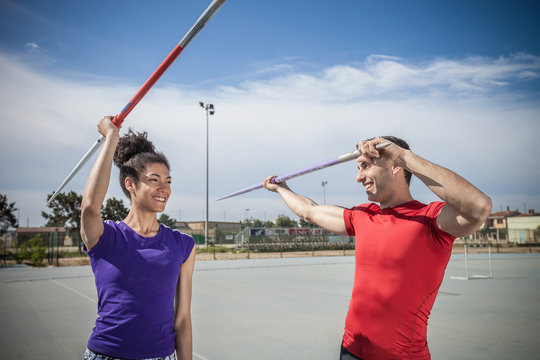 Man instructing female javelin thrower at sports ground