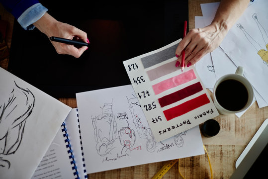 Overhead view of woman hands sketching fashion design on computerised sketch pad