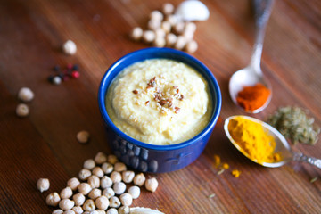 Hummus, chickpea dip, with rosemary, smoked paprika and olive oil in an authentic bowl with pita on a wooden background.