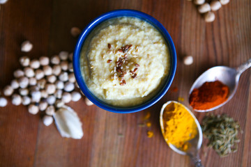 Hummus, chickpea dip, with rosemary, smoked paprika and olive oil in an authentic bowl with pita on a wooden background.