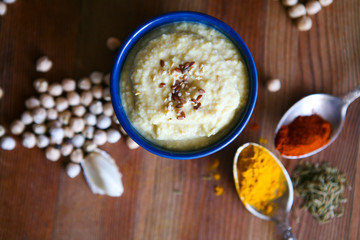Hummus, chickpea dip, with rosemary, smoked paprika and olive oil in an authentic bowl with pita on a wooden background.