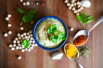 Hummus, chickpea dip, with rosemary, smoked paprika and olive oil in an authentic bowl with pita on a wooden background.