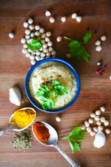 Hummus, chickpea dip, with rosemary, smoked paprika and olive oil in an authentic bowl with pita on a wooden background.