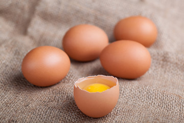 Fresh eggs on sacking, broken eggshell, yolk