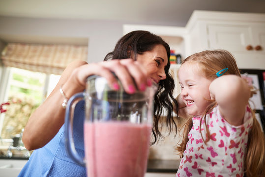 Mother and daughter making smoothies in noisy blender