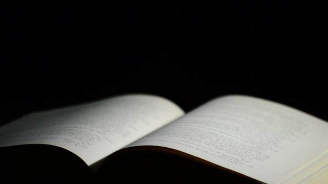 Page of a old open book with words, phrases and texts in castillian, rotating