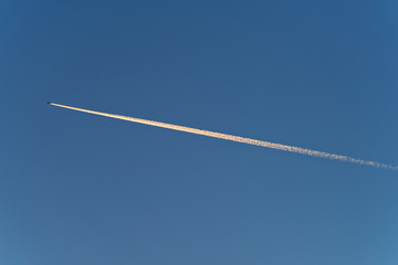 Trace of jet plane on blue sky at sunset