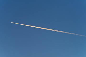 Trace of jet plane on blue sky at sunset