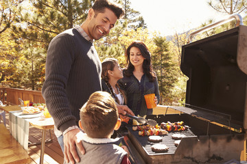 Family barbecuing on a deck in the forest - obrazy, fototapety, plakaty