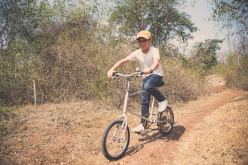 Fototapeta premium Little boy ride bicycle on the rock road.