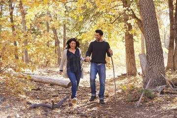 Fototapeta premium Smiling Hispanic couple walk in a forest holding hands