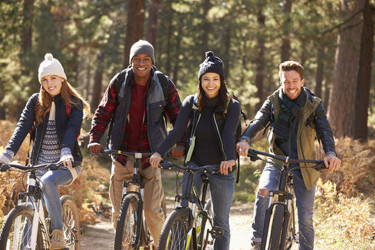 Group of four friends on bikes in a forest looking to camera