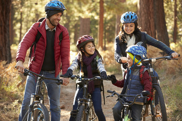 Fototapeta na wymiar Hispanic family on bikes in a forest looking at each other