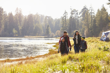 Family on camping trip walk near lake, looking at each other