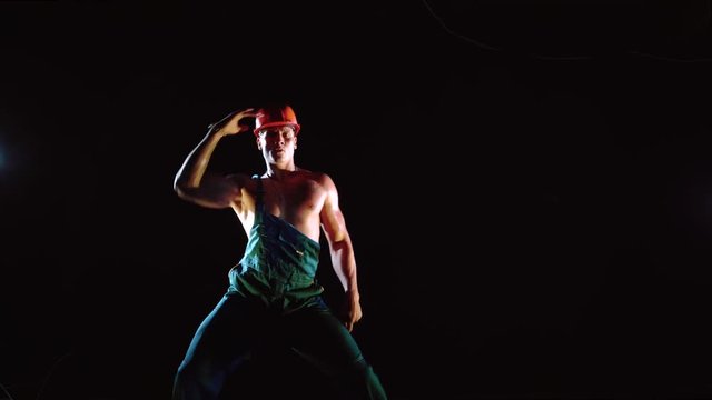 Young handsome builder sexy dancing on dark background