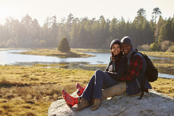 Mixed race couple on a rock in countryside looking to camera