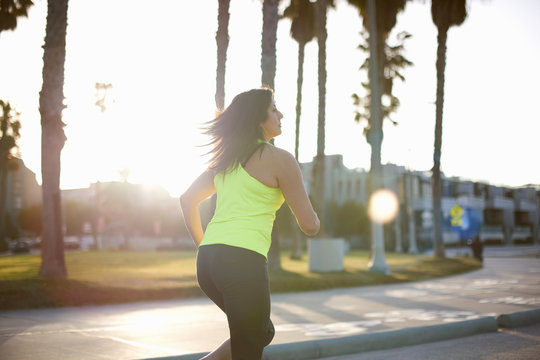 Side view of woman wearing neon vest jogging