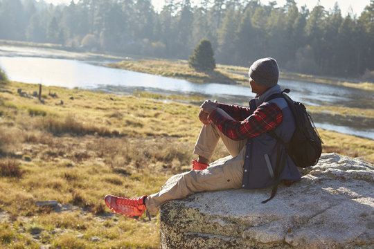 Young black man sitting alone on a rock in countryside