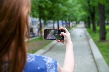 Young woman taking a photo with her phone in the park