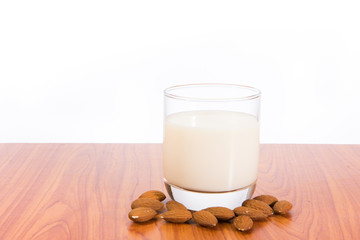 Almond milk in glass with almonds on wooden table