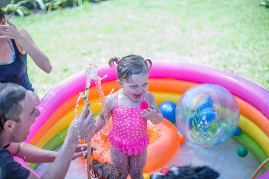 Parents, daughter and pet dogs playing in inflatable pool
