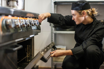 Chef adjusting temperature of oven in kitchen