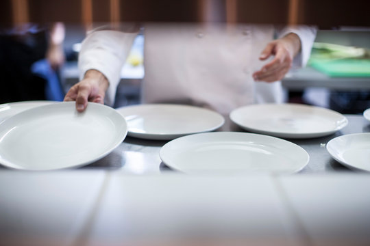Chef laying out empty plates in kitchen