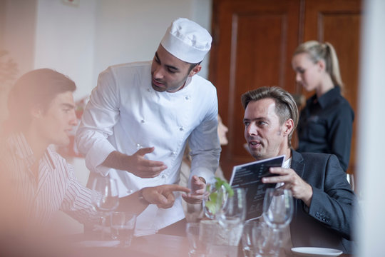 Chef chatting with customers in restaurant