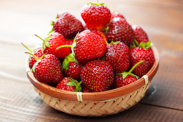 Very beautiful background with fresh strawberries in a wicker round osier basket on old brown...