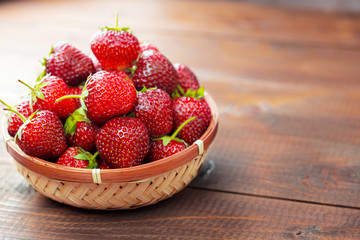 Very beautiful background with fresh strawberries in a wicker round osier basket on old brown...